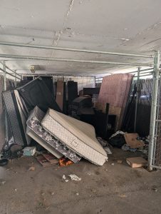 A large amount of bulky waste left in front of a dumpster at an apartment building in London Ontario