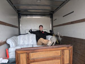 Mike Metcalfe giving the thumbs up from the back of the Get R Gone junk removal truck